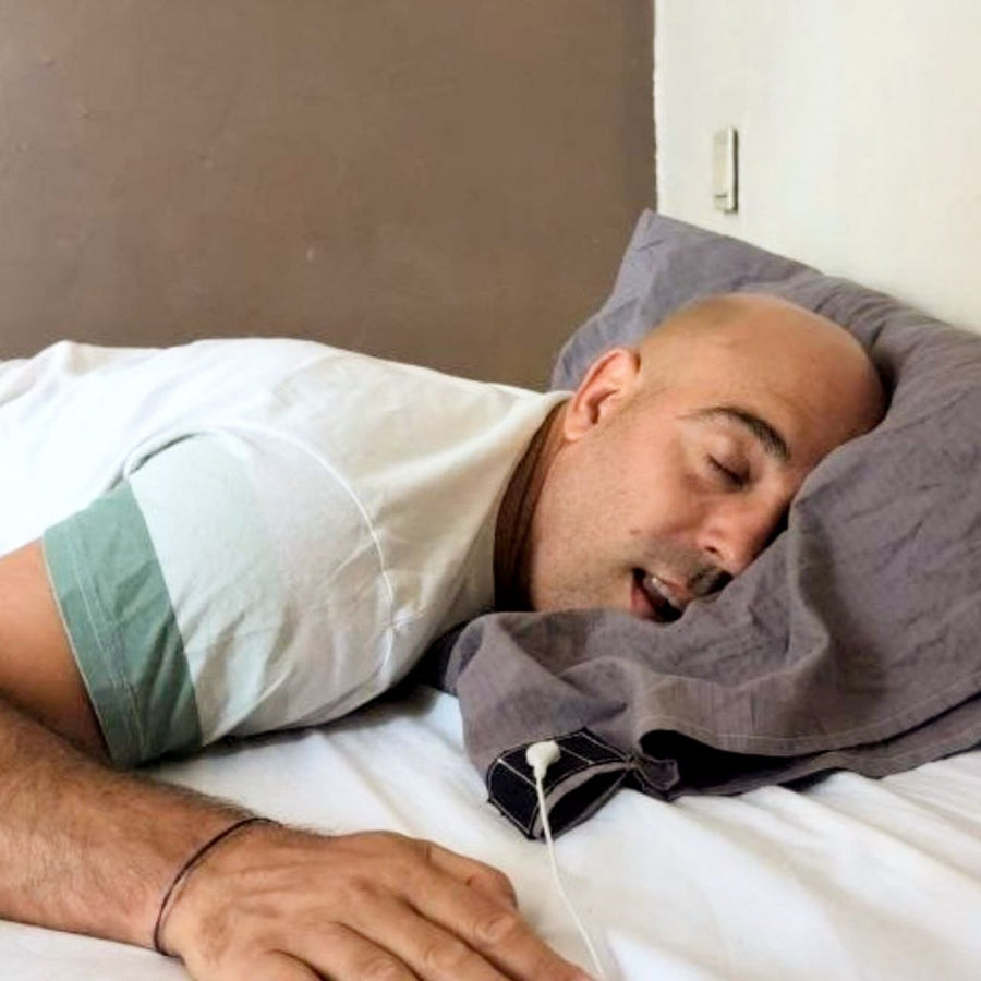 Homme endormi sur un lit connecté à la terre, clip et câble de mise à la terre visibles sur le drap